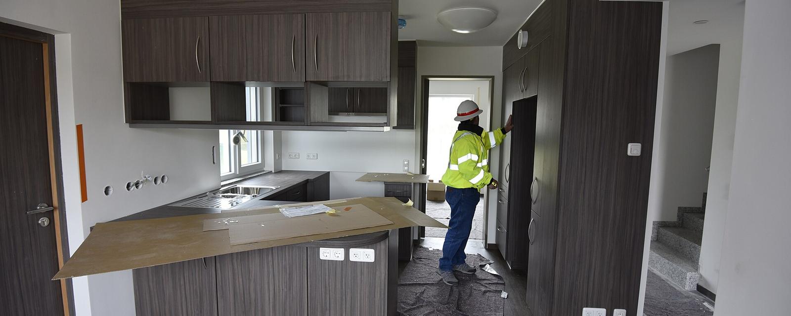 A kitchen being finished, with a worker in a safety vest
